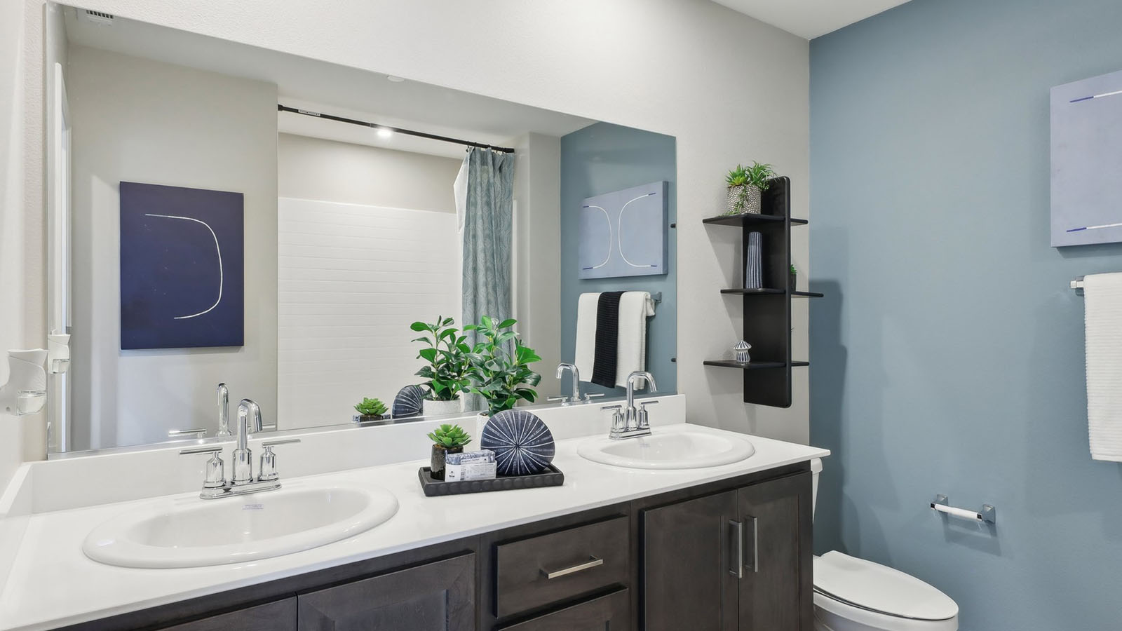 Secondary bedroom with dual sinks and brown cabinets