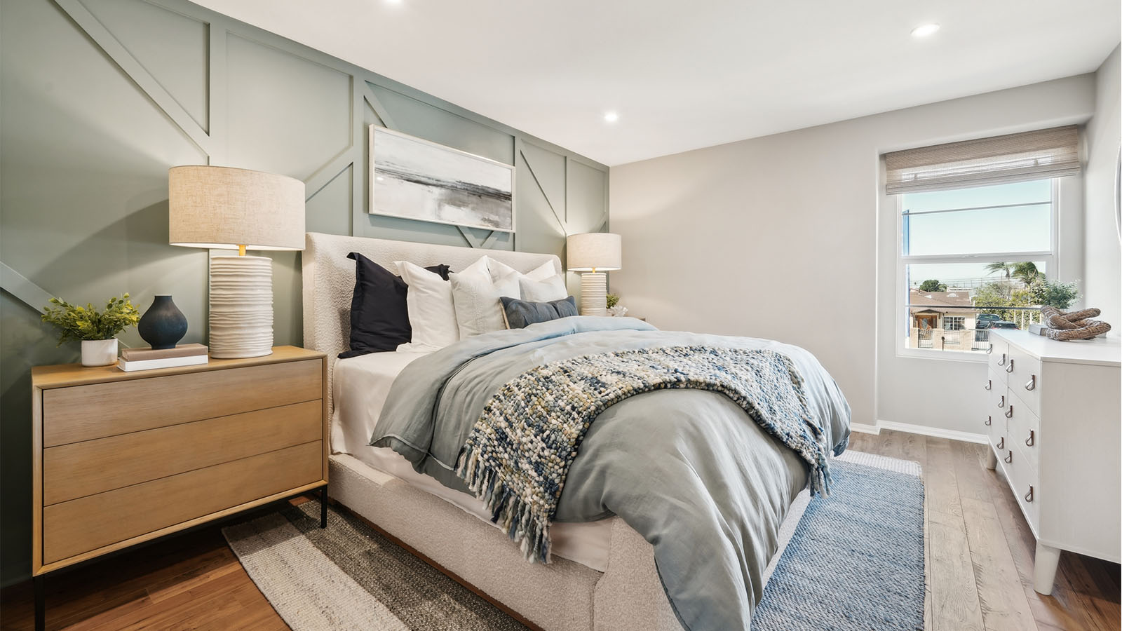 Primary bedroom with king bed, accent wall, and laminate flooring