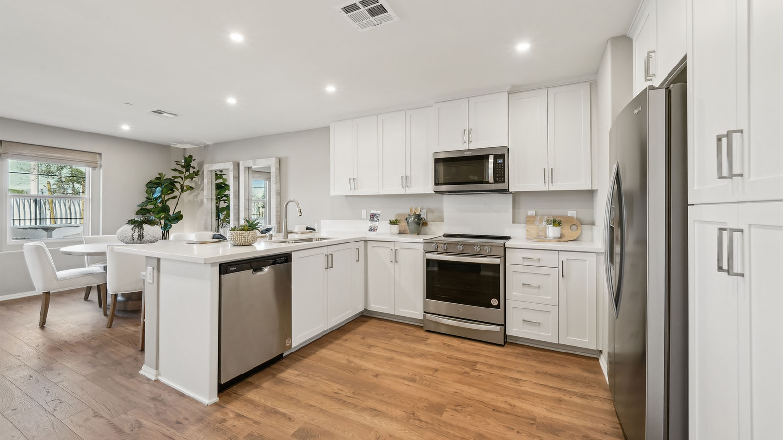 Modern open-concept kitchen with white cabinets and stainless steel applia