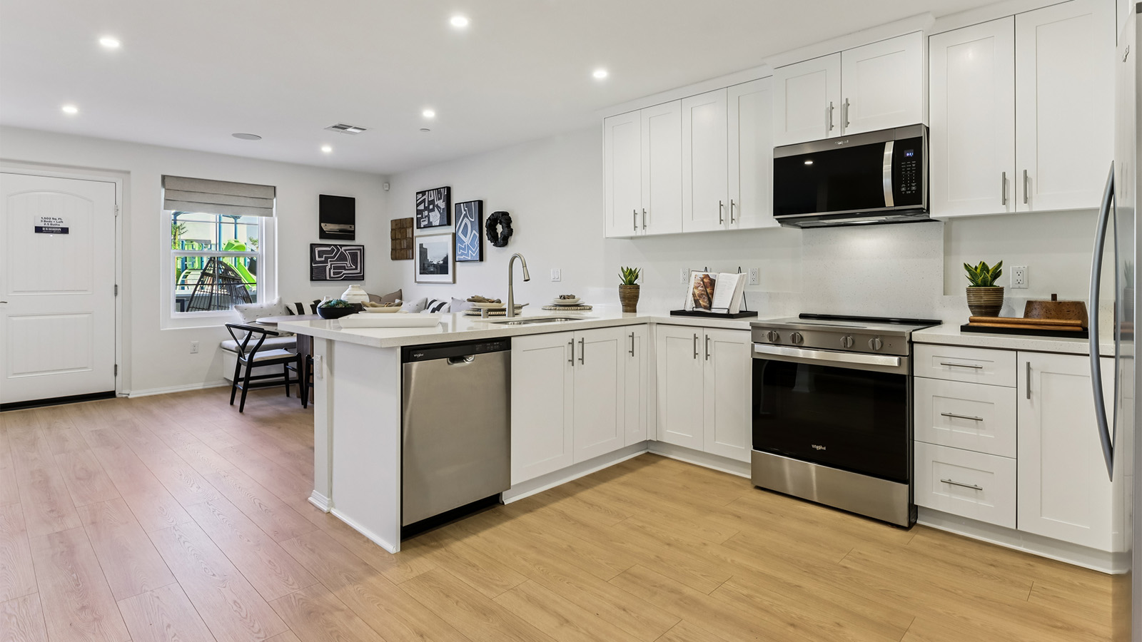 Modern open-concept kitchen with white cabinets and stainless steel appliances