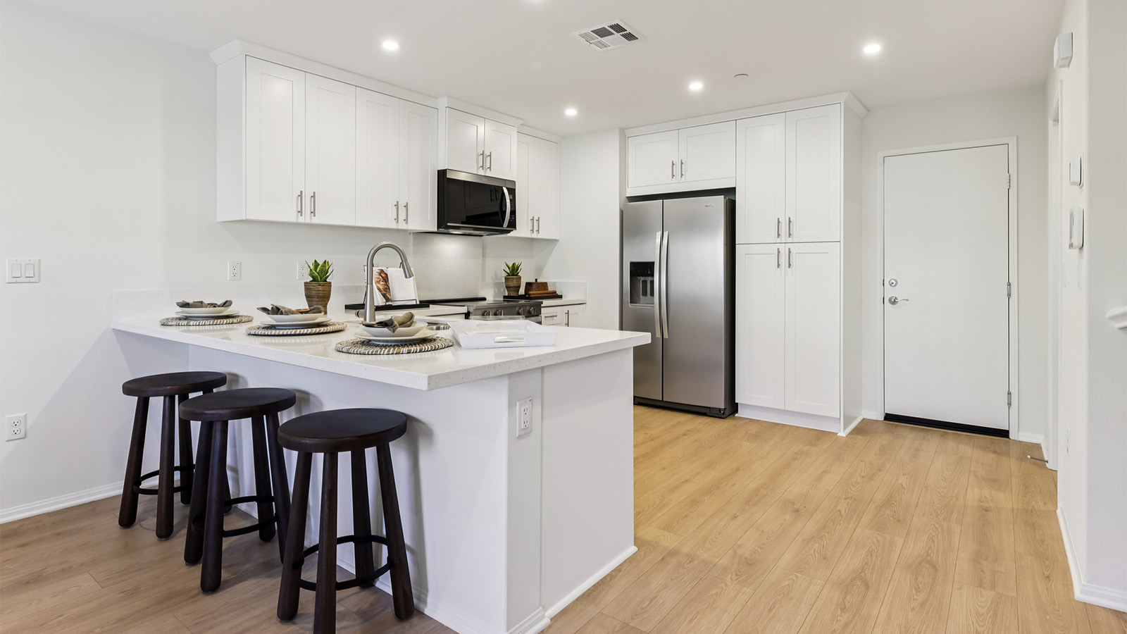 Modern open-concept kitchen with white cabinets and stainless steel appliances