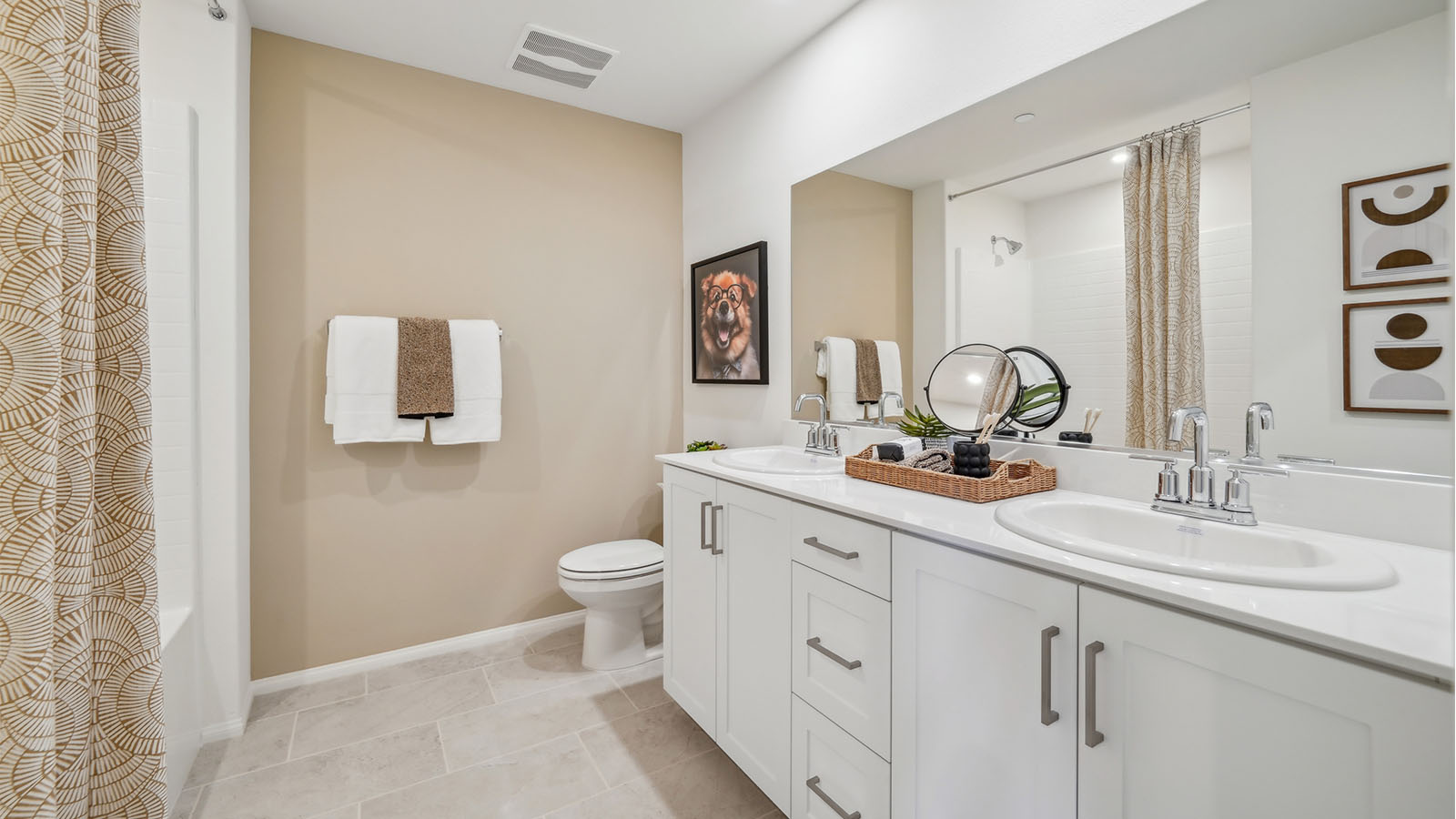 Secondary restroom with dual sinks, white cabinets and countertops, and shower