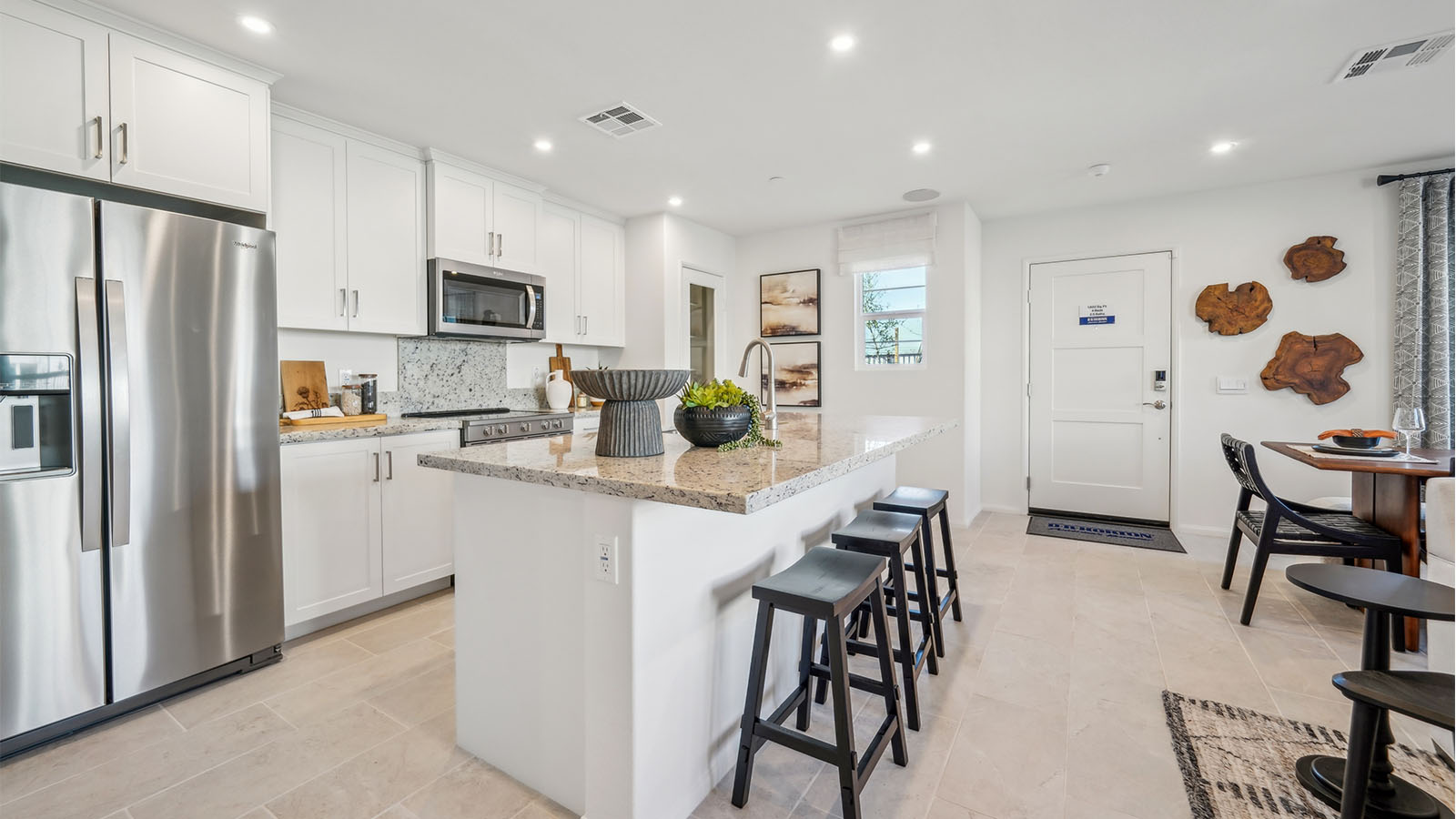 Modern open-concept kitchen with white cabinets, granite countertops and stainless steel applia