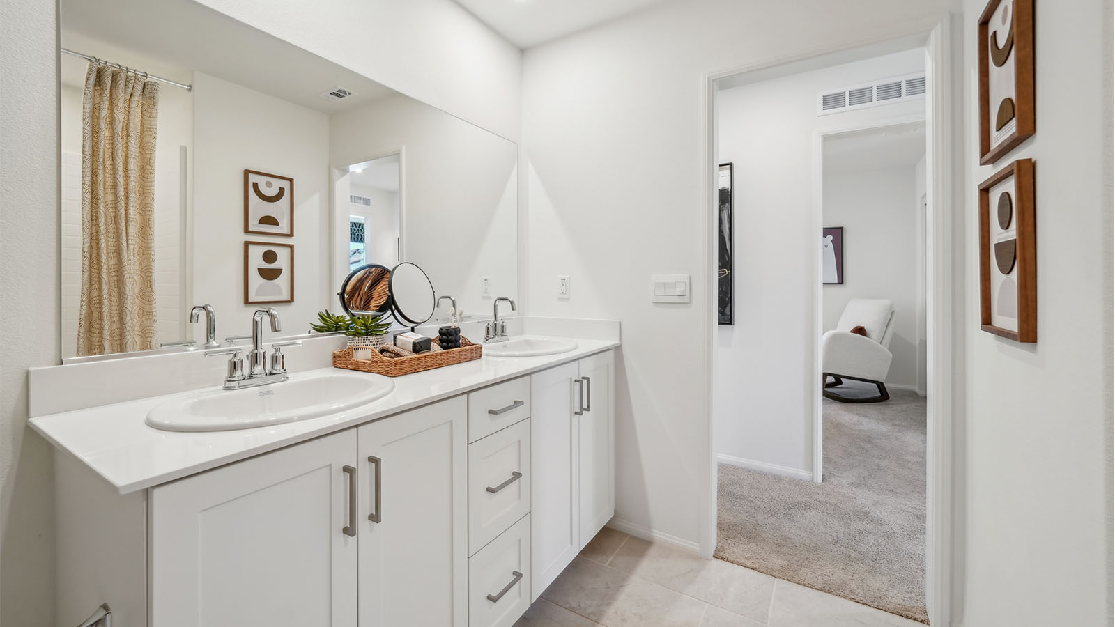 Secondary restroom with dual sinks, white cabinets and countertops, and shower