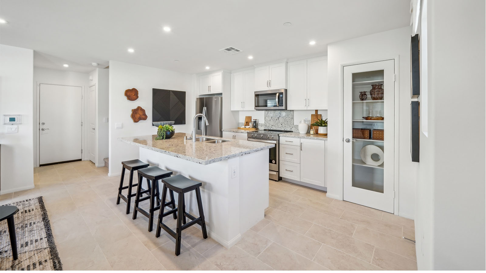 Modern open-concept kitchen with white cabinets, granite countertops and stainless steel applia