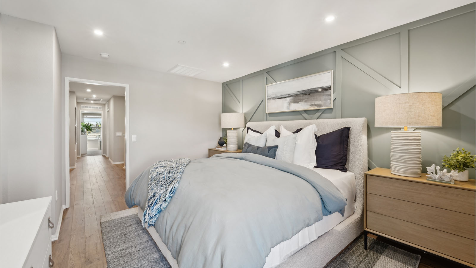 Primary bedroom with king bed, accent wall, and laminate flooring