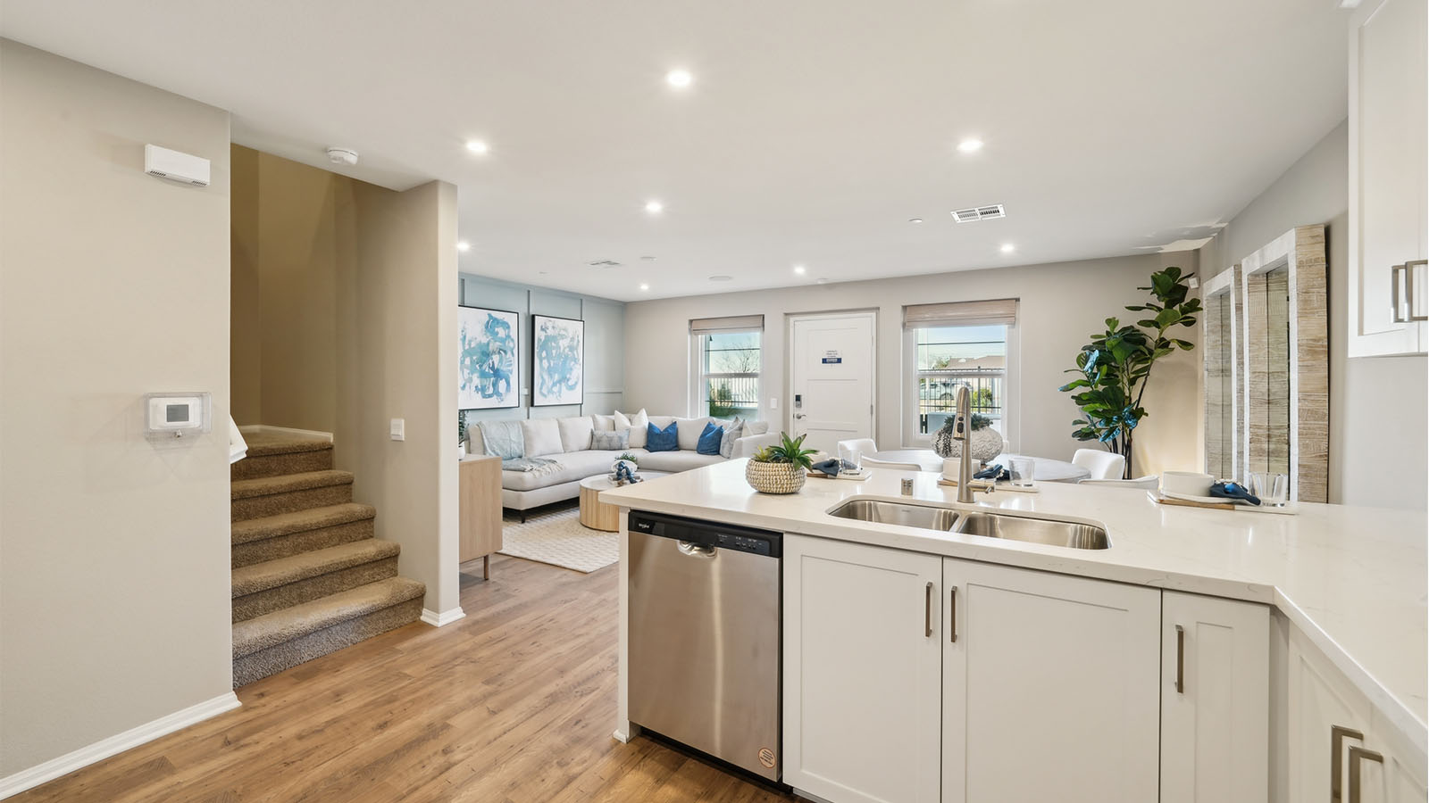 Modern open-concept kitchen with white cabinets and stainless steel applia