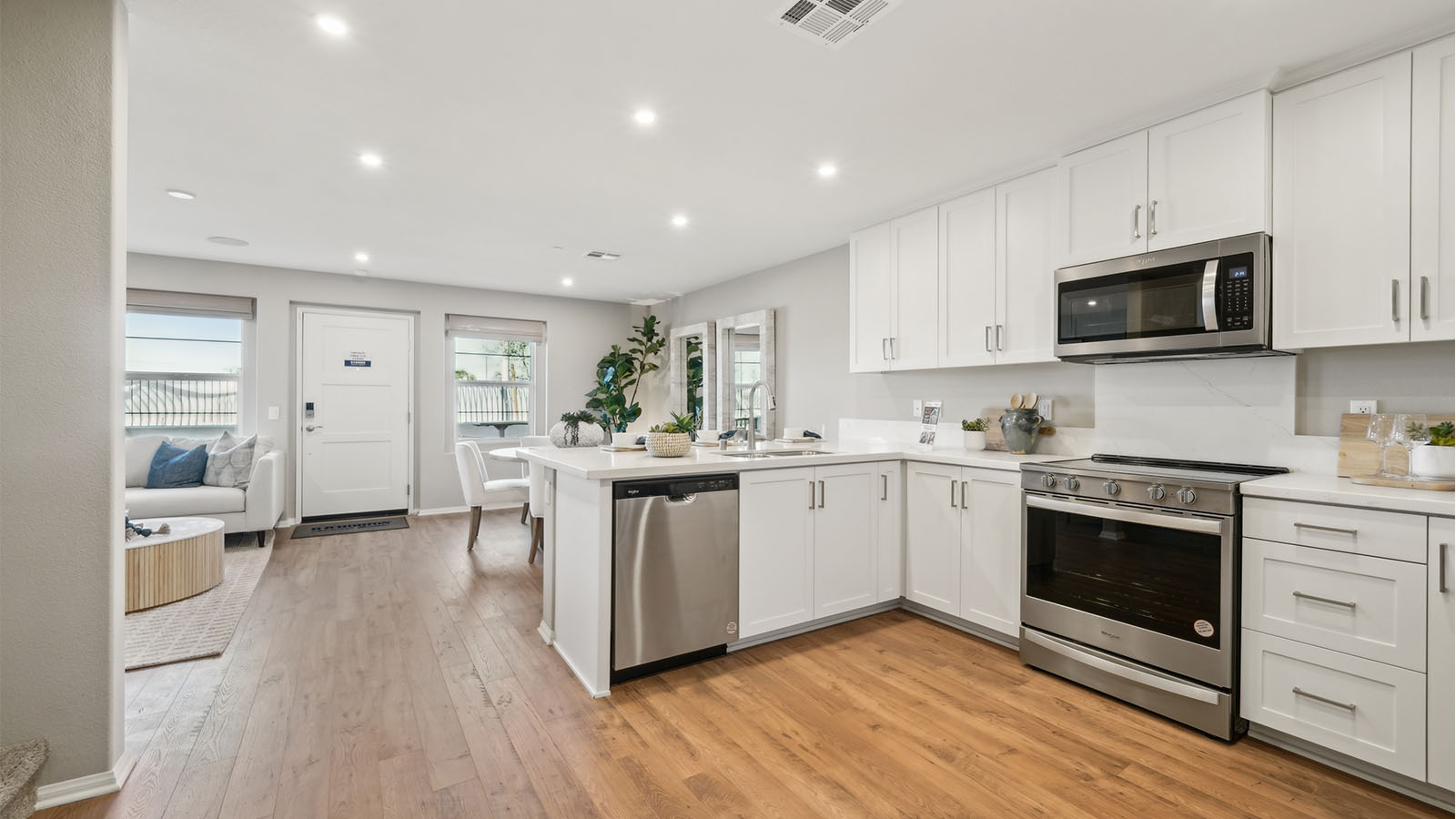 Modern open-concept kitchen with white cabinets and stainless steel applia