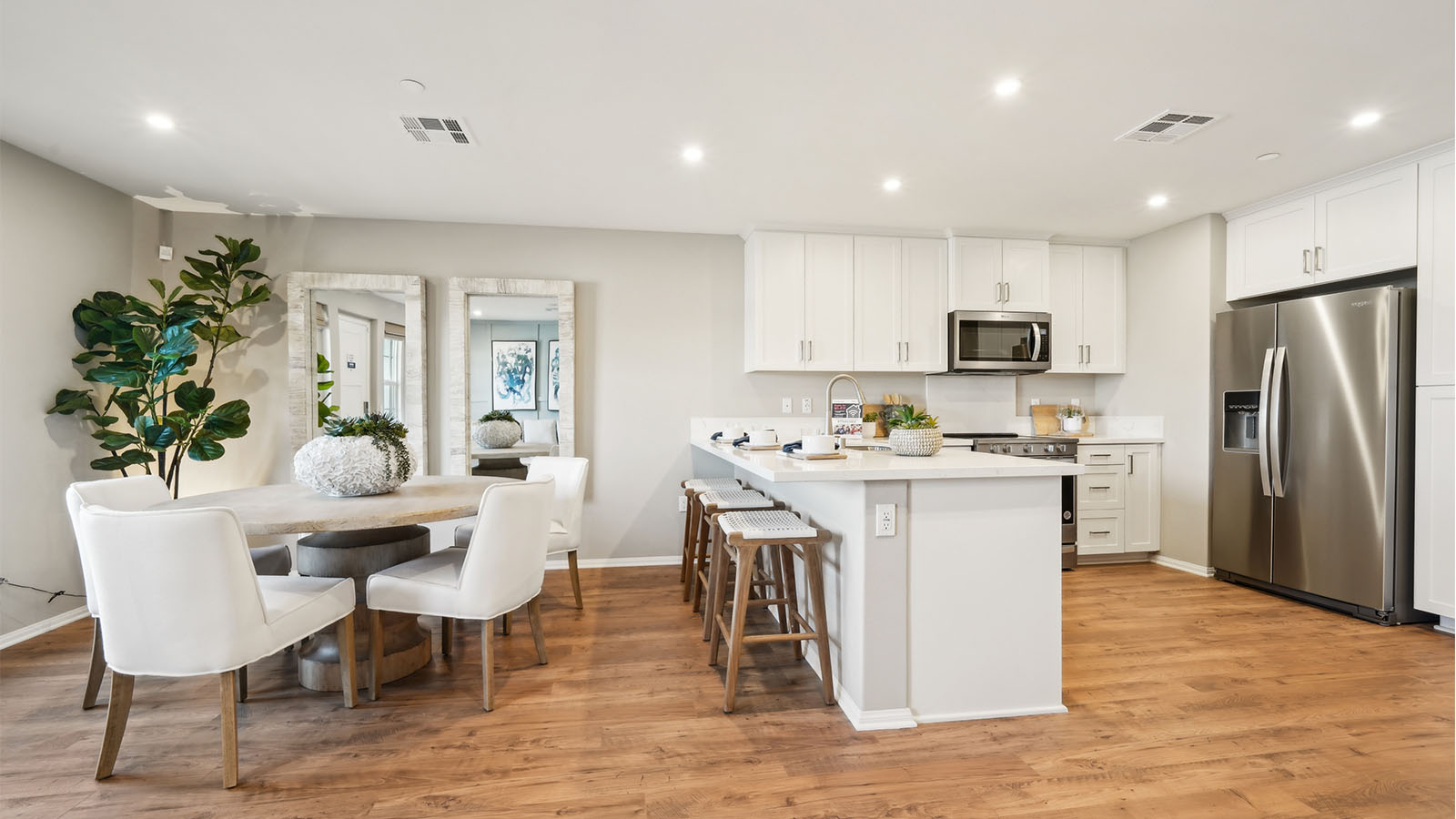 Modern open-concept kitchen with white cabinets and stainless steel applia