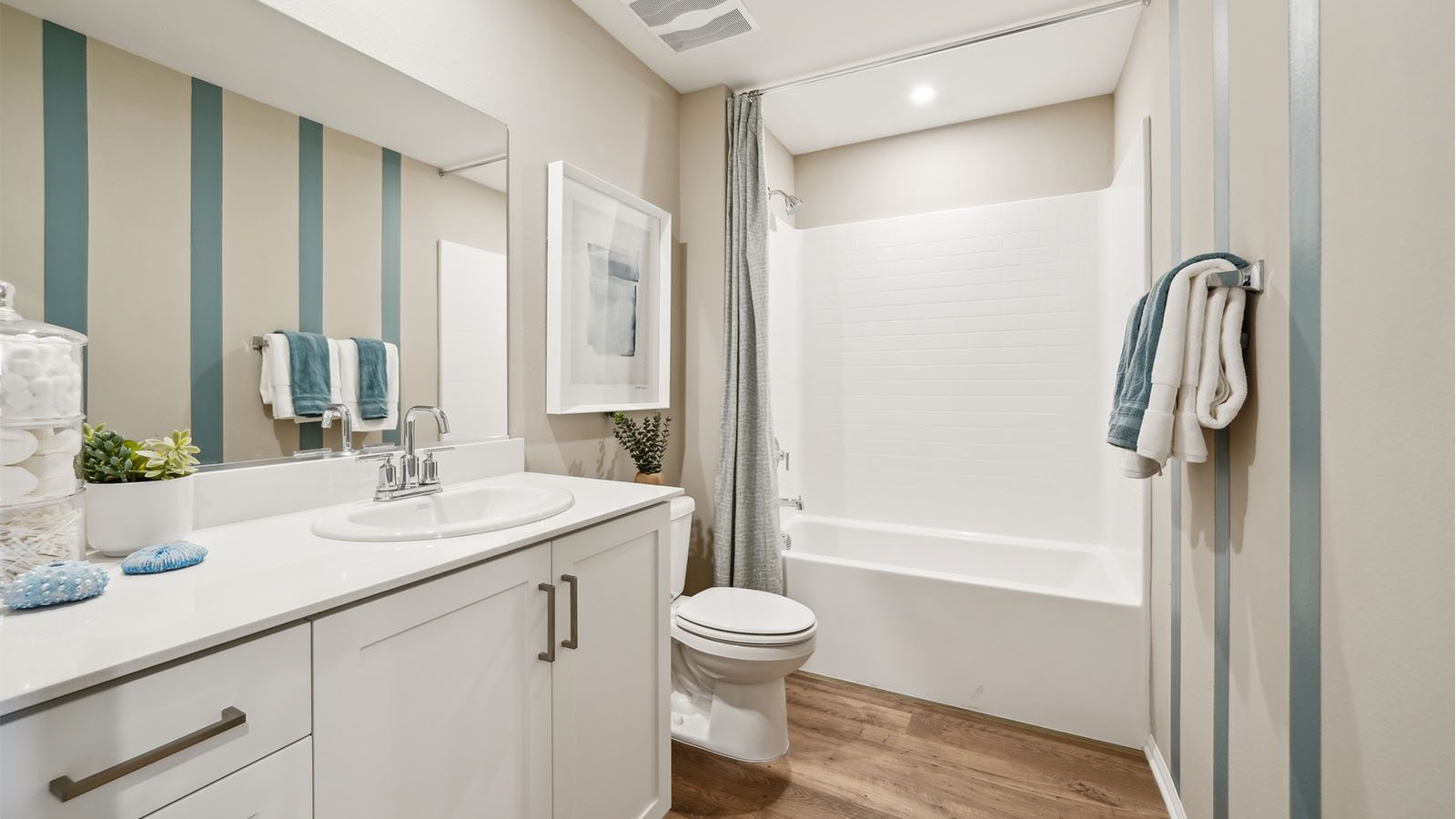 Bathroom with shower and white cabinets with laminate flooring