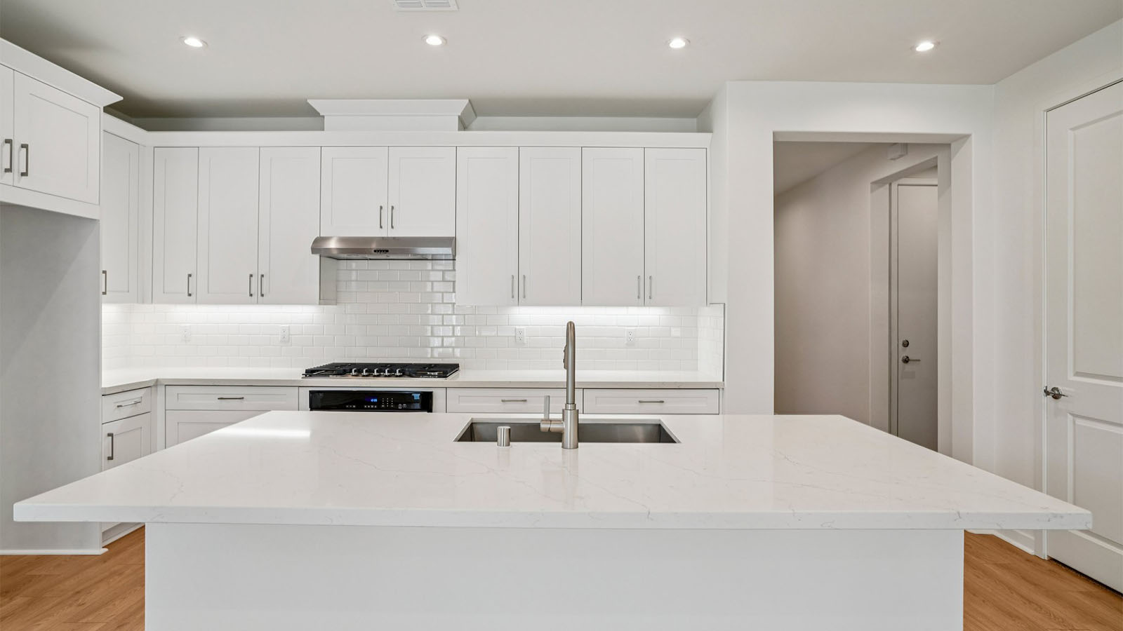 Open-concept kitchen with white cabinets and stainless steel appliancees