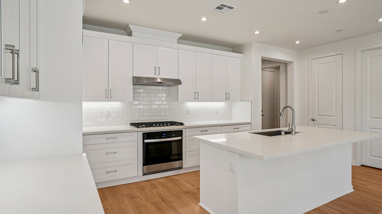 Open-concept kitchen with white cabinets and stainless steel appliancees