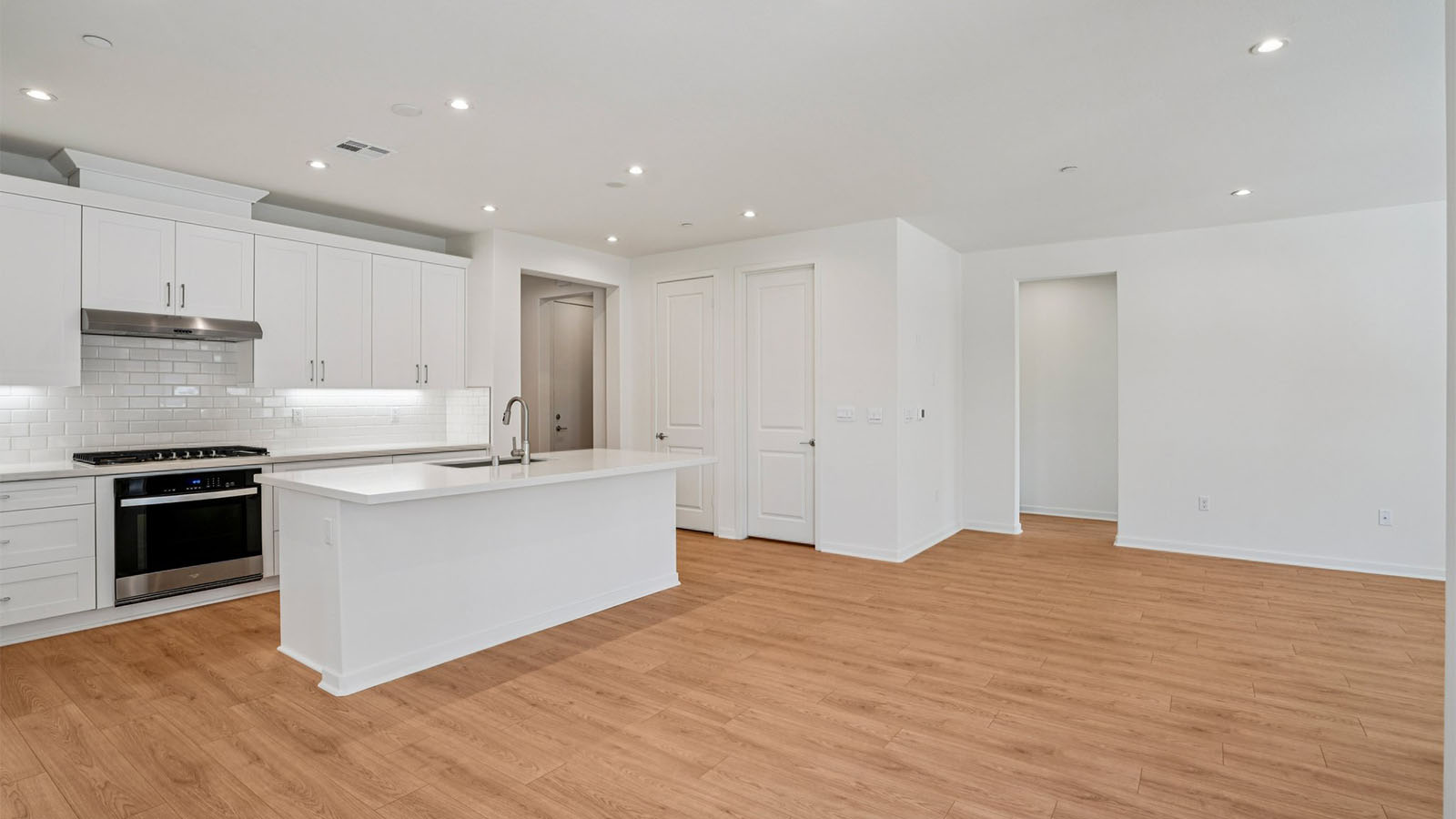 Open-concept kitchen with white cabinets and stainless steel appliancees