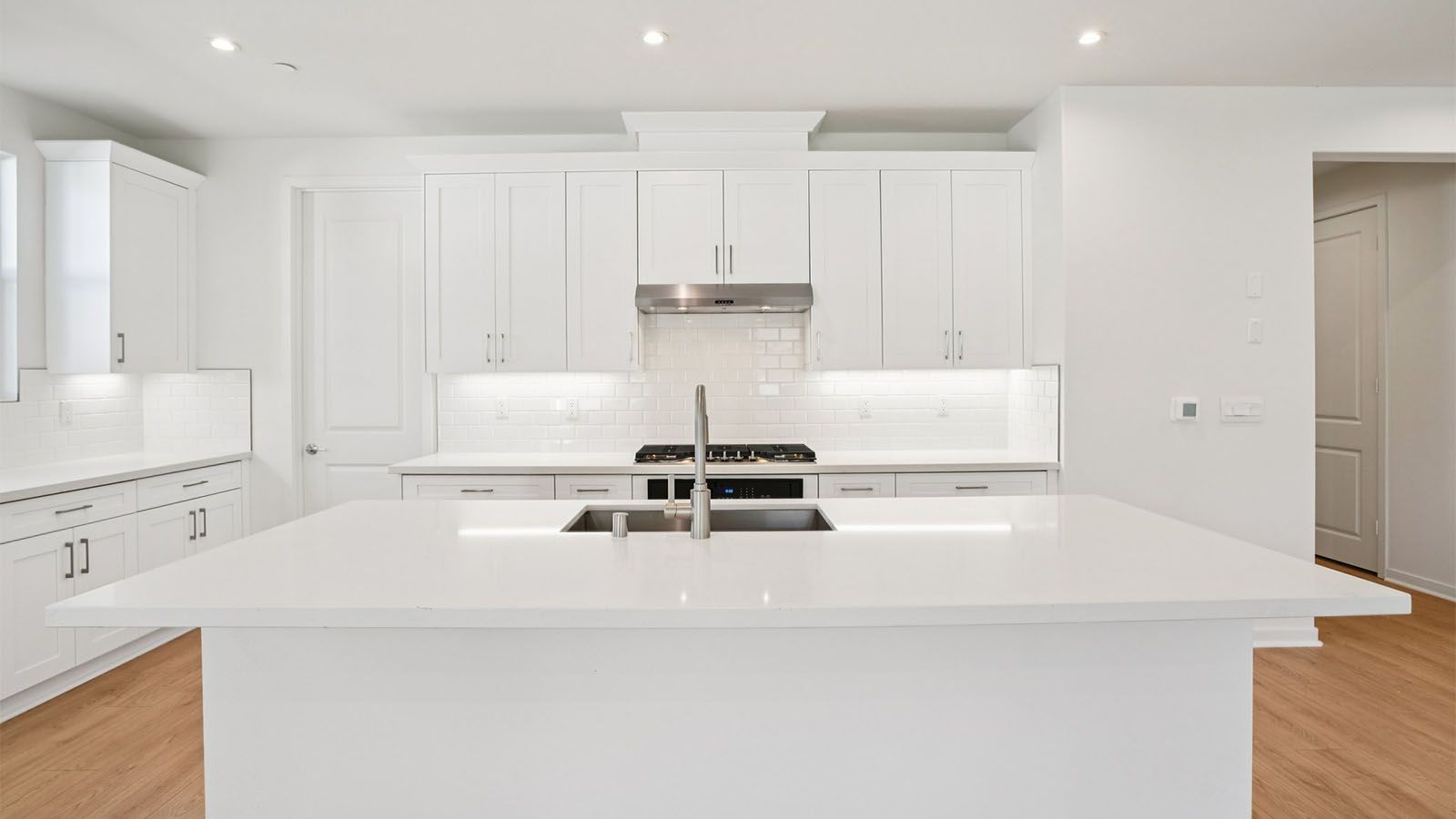Open-concept kitchen with white cabinets and stainless steel appliances