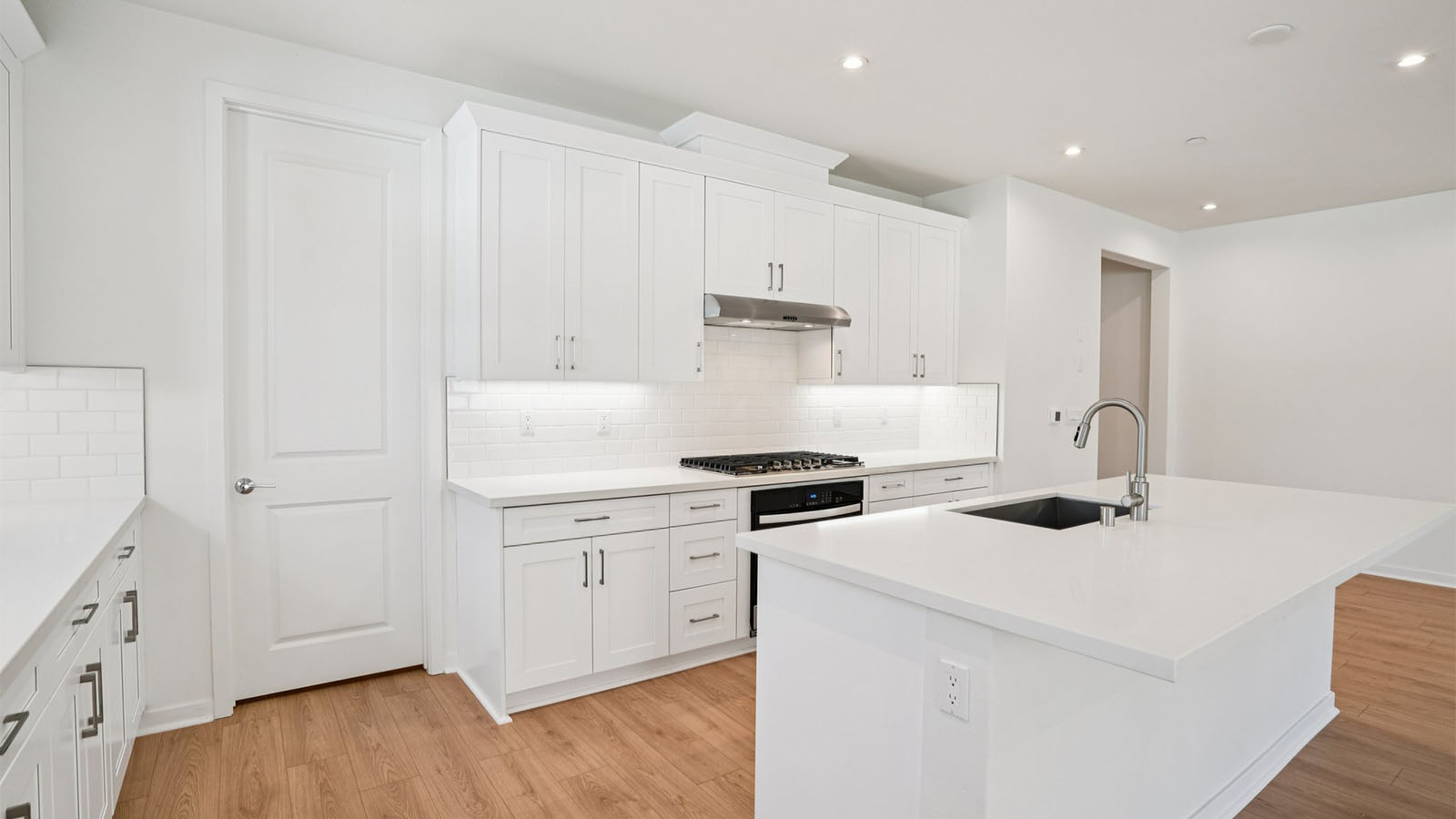 Open-concept kitchen with white cabinets and stainless steel appliances