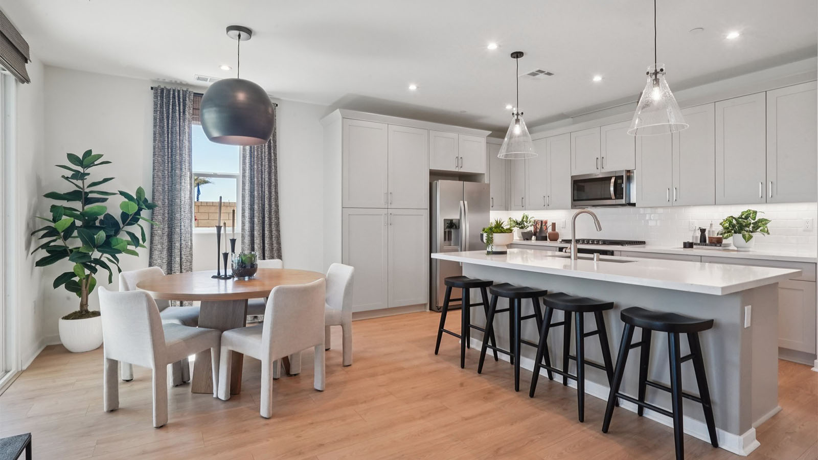 Modern kitchen with tan cabinets quartz countertops and stainless steel appliances and dining room