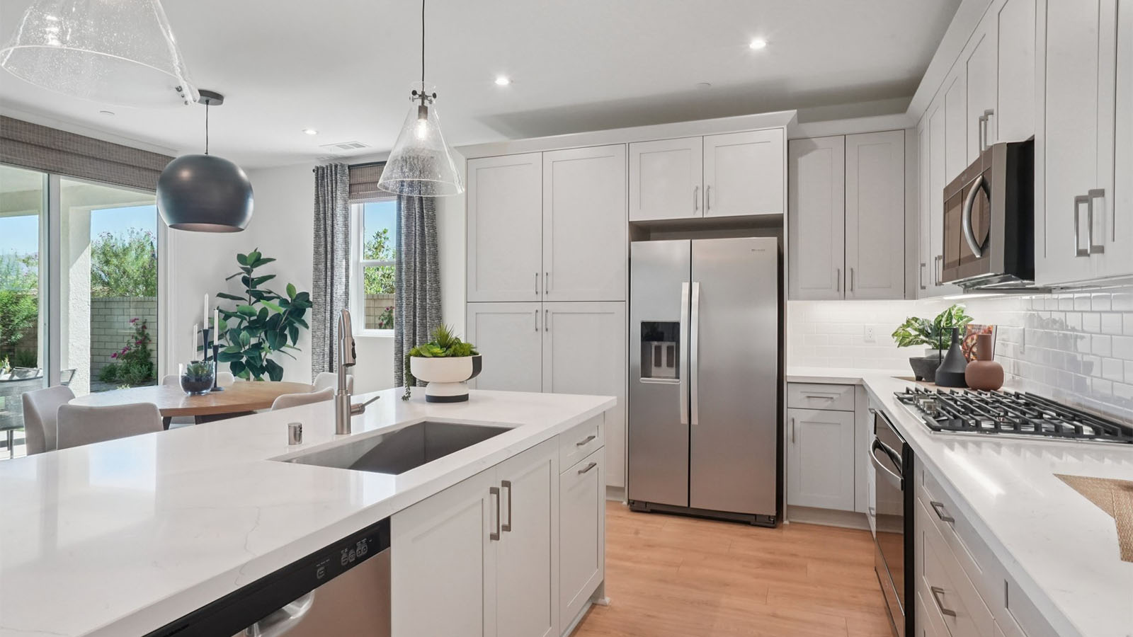 Modern kitchen with tan cabinets quartz countertops and stainless steel appliances and dining room