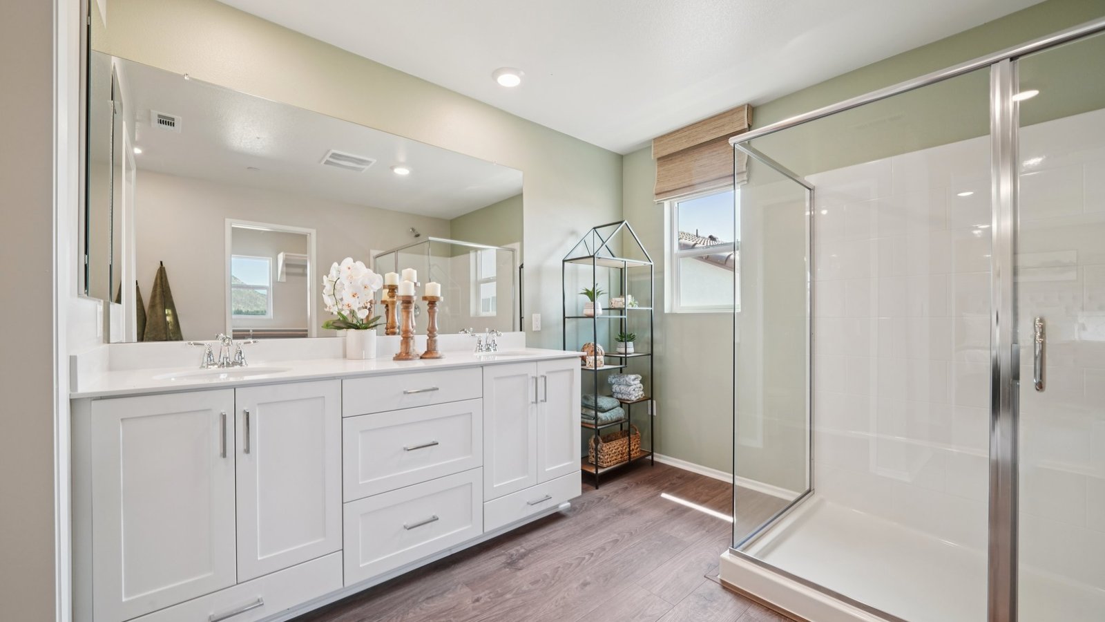 primary bathroom with dual vanities and shower