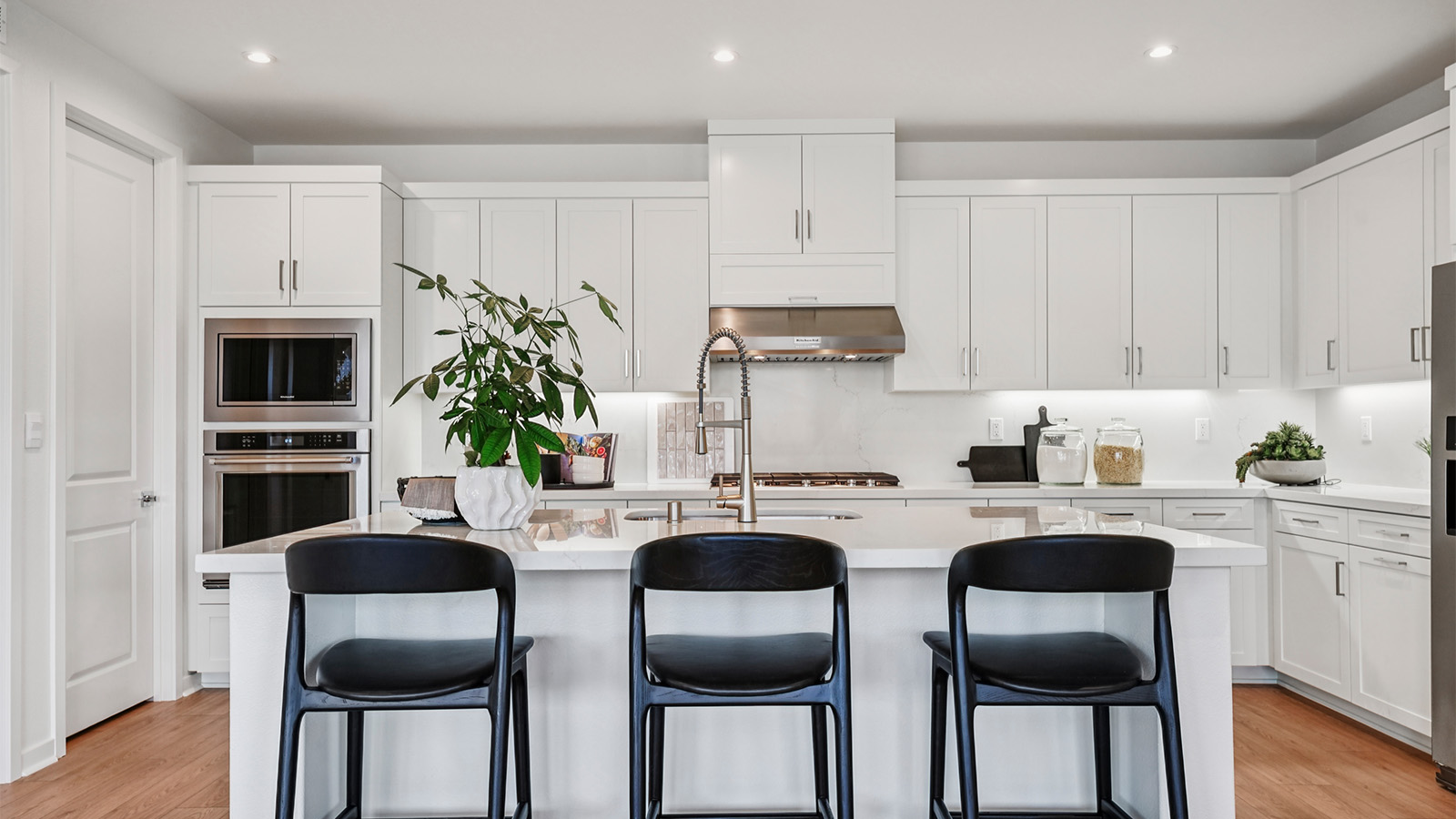 Kitchen with white cabinets, and an island with room for seating