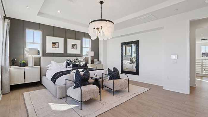 Interior primary bedroom with accent wall and large windows