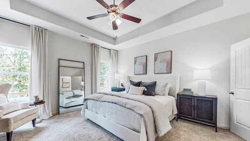 Destin – Primary Bedroom -  The large oversized primary bedroom features trey ceilings, carpet, a king sized bed, nightstands, and a dresser