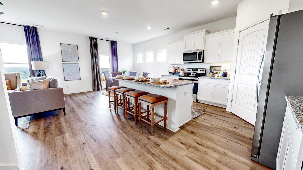 Oversized kitchen with a large island, stainless steel appliances, white cabinets and a walk in pantry that over look the large living room and breakfast nook