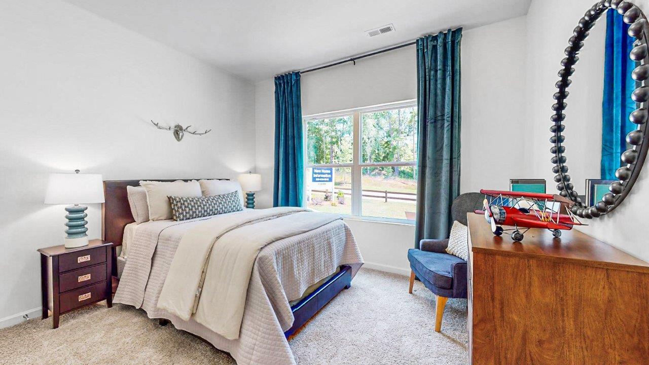 The spacious fourth bedroom is furnished with a queen-sized bed, a dresser, two nightstands, and an accent chair. There is still ample space available in the room, allowing for comfortable movement and additional furniture if desired.