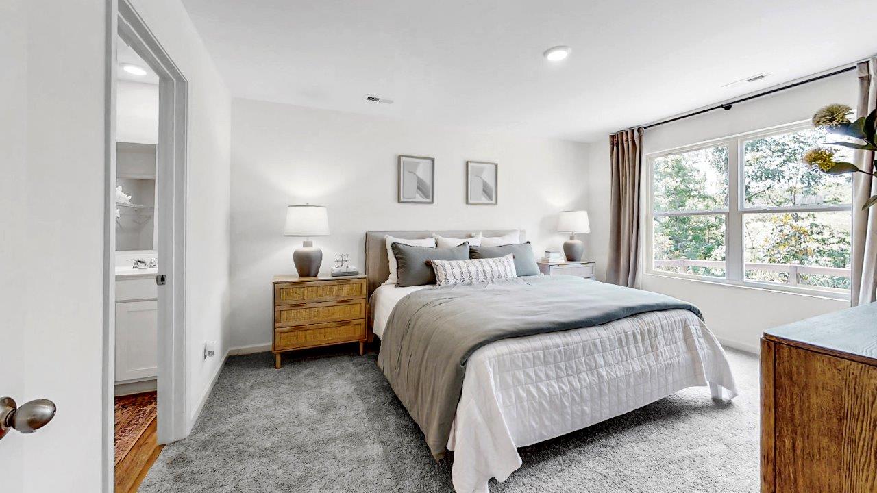 Large primary bedroom shows off ample space with a large king bed, 2 nightstand and a large double window that overlooks the backyard