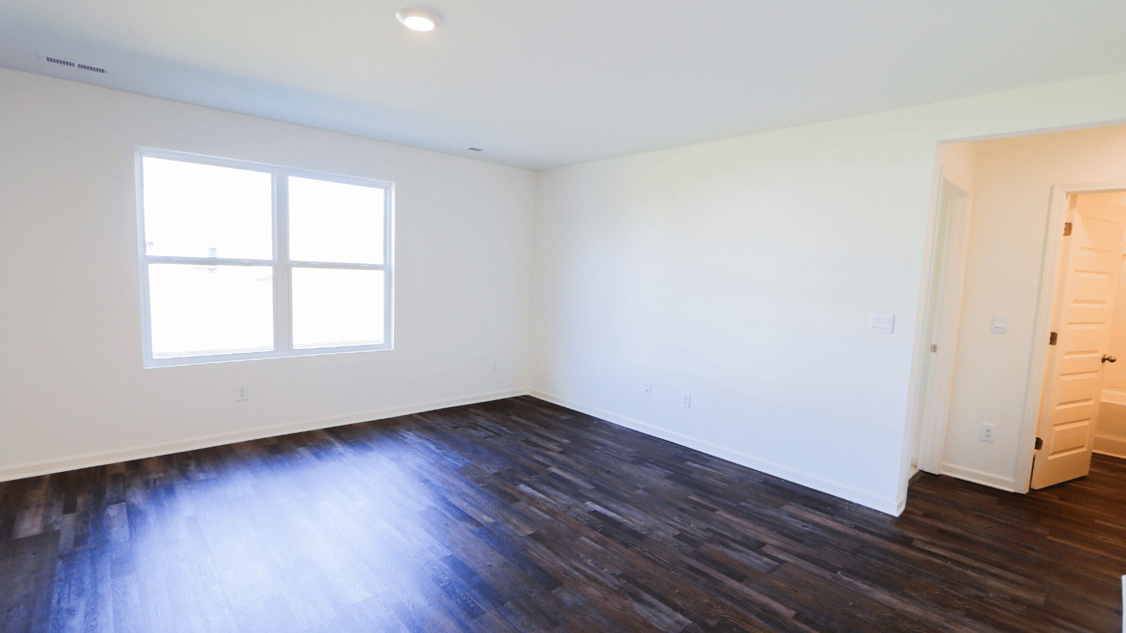 Bright, spacious room with large windows, wood flooring, and neutral walls, ideal for living or office space.