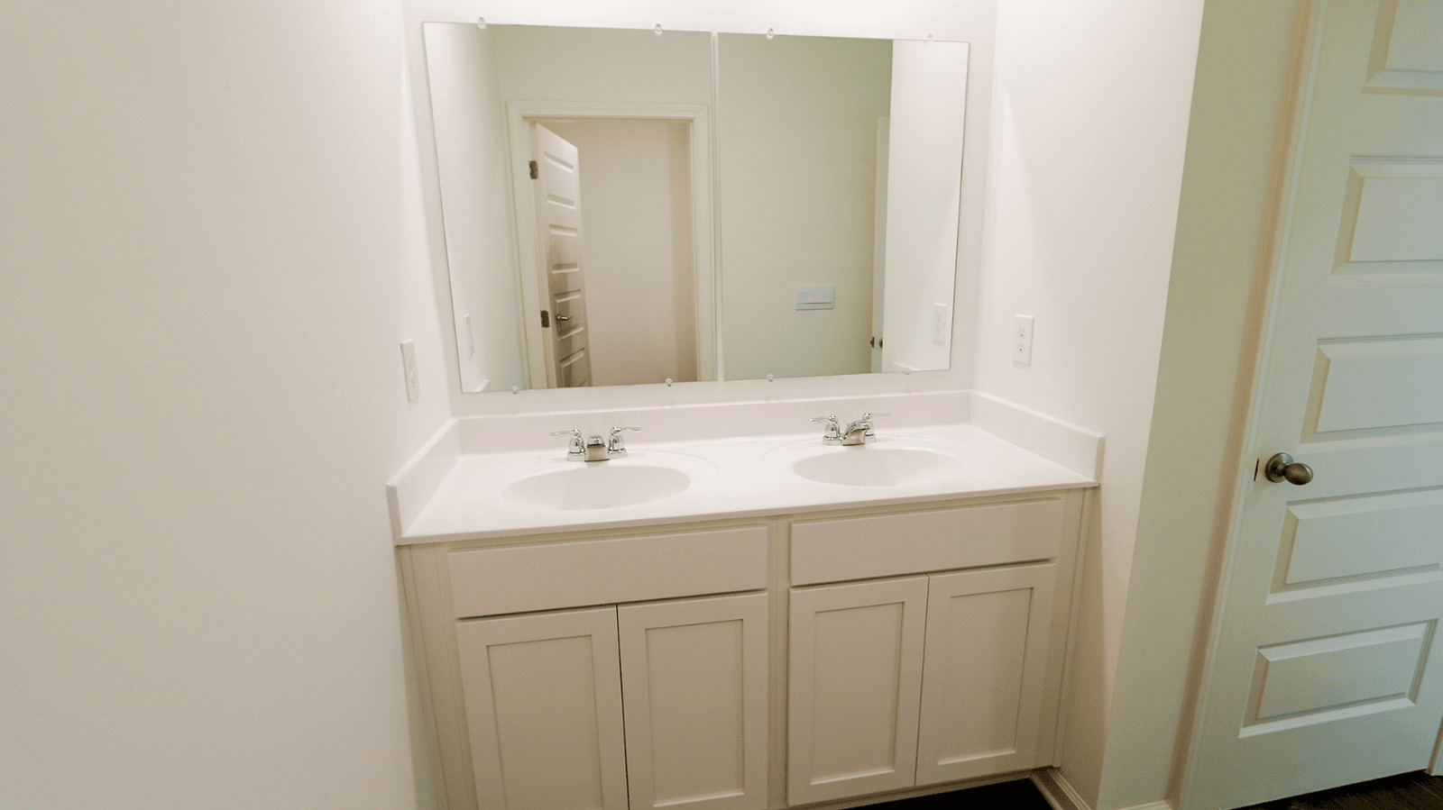 Double sink bathroom vanity with mirrors and modern fixtures, featuring light-colored cabinetry and a clean aesthetic.