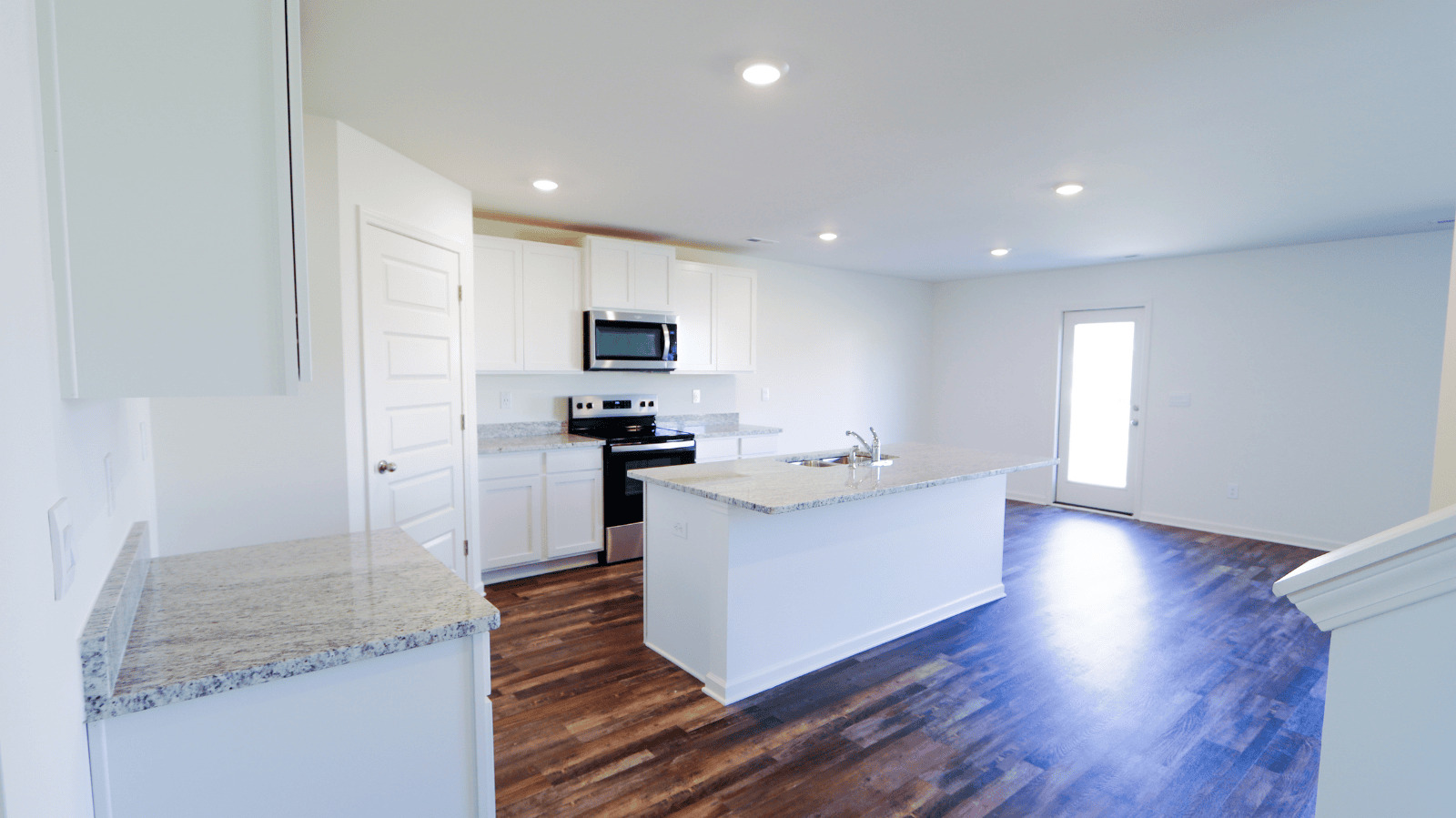 Open-concept kitchen space featuring stainless steel appliances, granite countertops, and natural light from the patio door.