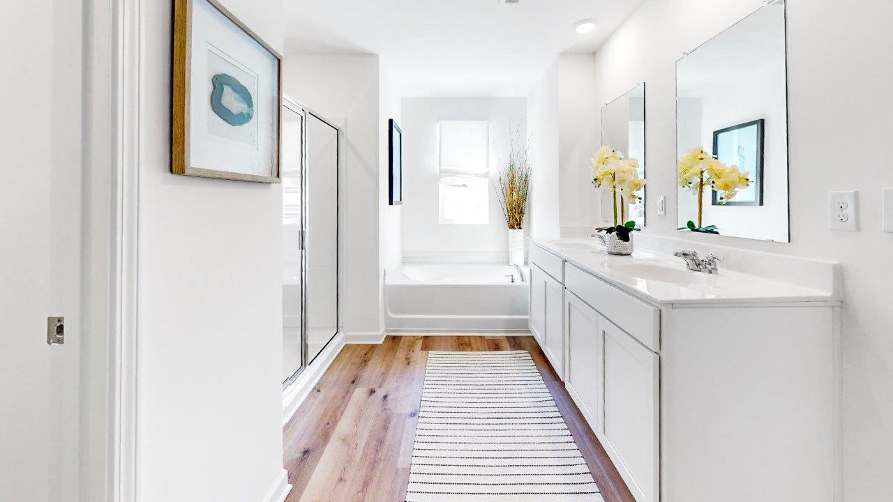 The large primary bathroom has a double vanity, a walk in shower, and a large garden tub