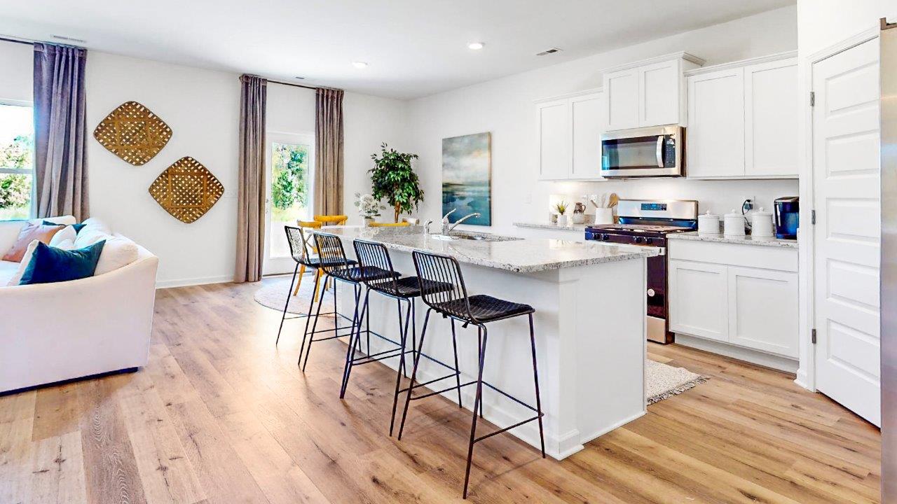 Oversized kitchen with a large island, stainless steel appliances, white cabinets and a walk in pantry that over look the large living room and breakfast nook