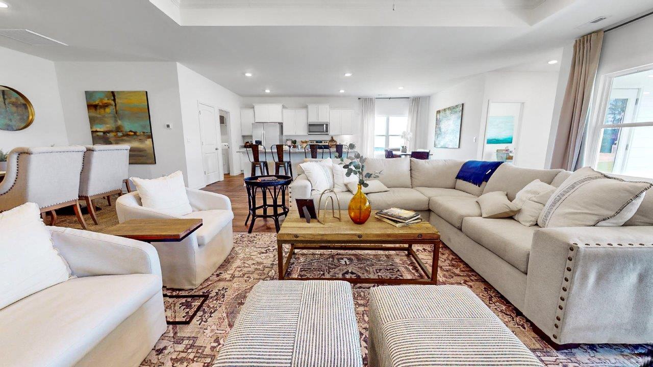 Living room with a large sectional couch opens up to the formal dining area as well as the kitchen and breakfast nook.