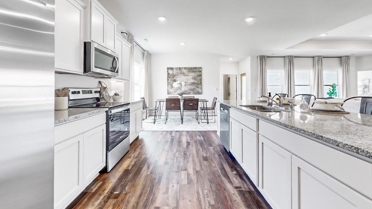 Open concept kitchen features a large island, white cabinets, stainless steel appliances and opens the full breakfast nook