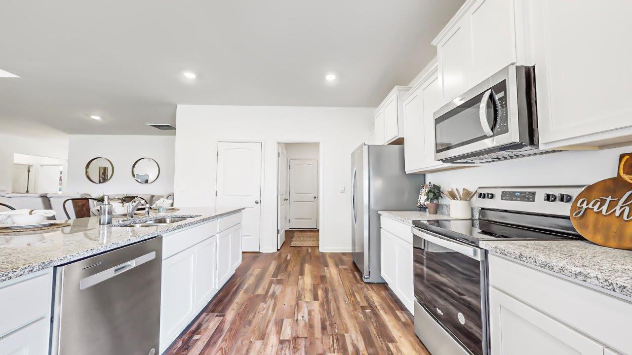 Kitchen which features white cabinets and stainless steel appliances also has a walk-in pantry as well as the laundry room which opens to the garage