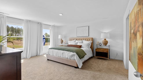 Penwell – Primary Bedroom -1 – A very spacious bedroom featuring a king-sized bed, 2 nightstands, a dresser, a chair and side table and a door that leads to the primary bathroom