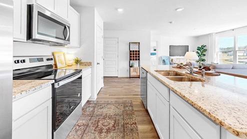 The kitchen is designed with a chef's inspiration, incorporating a pantry, stainless steel appliances, and a spacious kitchen island. The pantry offers ample storage space for ingredients, while the stainless-steel appliances provide a modern and sleek aesthetic to the kitchen. The large kitchen island serves as a multifunctional space for food preparation, dining, and socializing, adding both practicality and style to the kitchen.