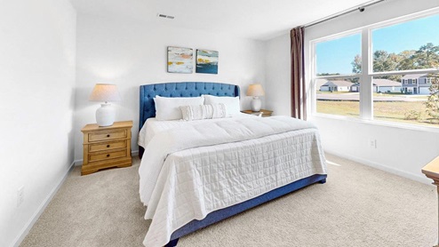 The primary bedroom features a spacious king-sized bed and two large windows.