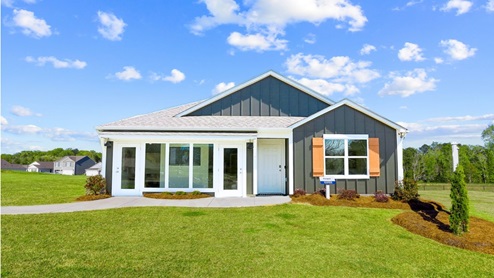 A spacious freeport model home surrounded by a large, lush green yard, featuring well-maintained grass and ample outdoor space.