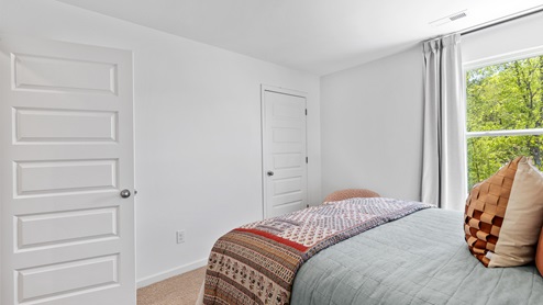 The primary bedroom has enough space for a king sized bed, two nighstands, a dresser, and a seating area.