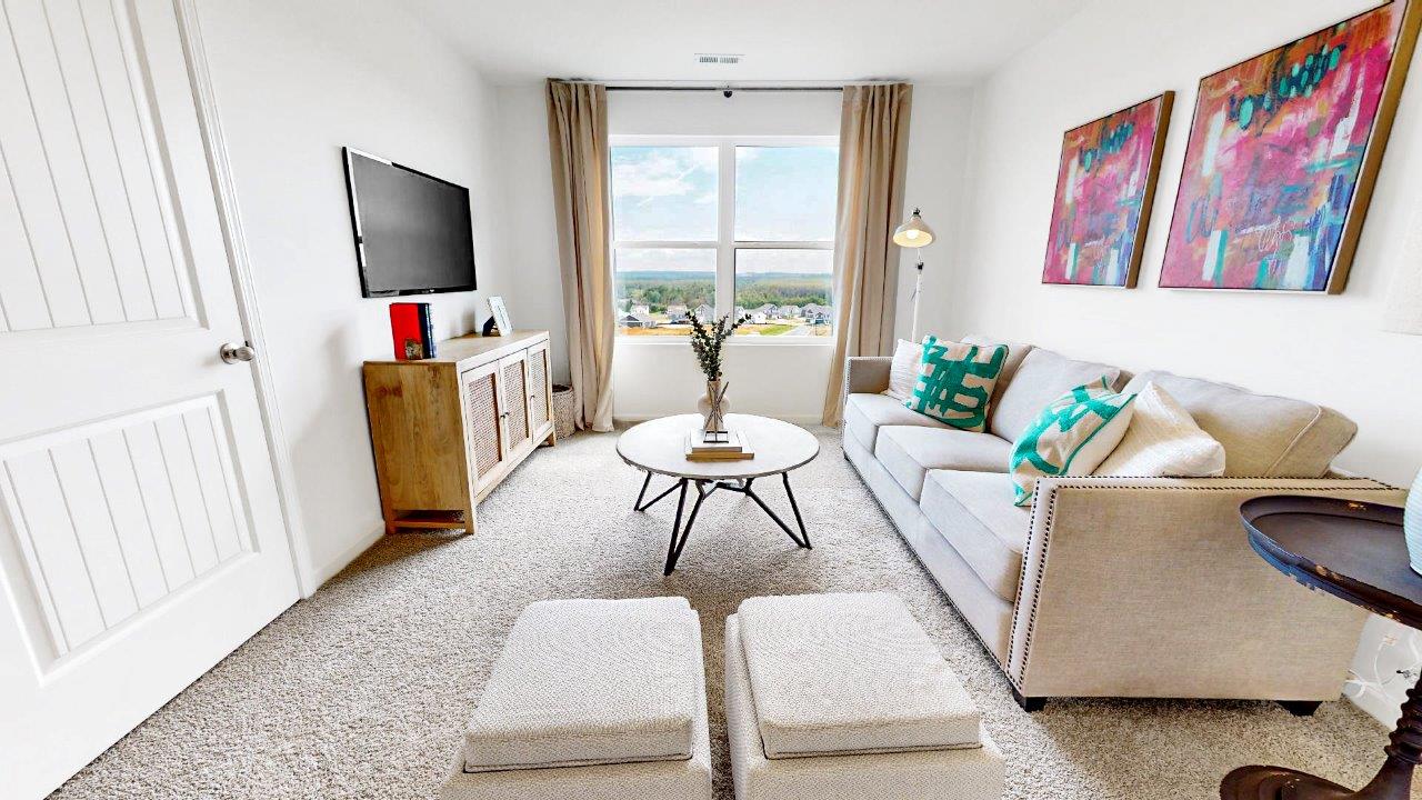 Loft style bonus room is great for entertaining or a play area for children with a couch and media consol