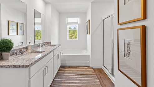 The spacious primary bathroom features a double vanity, providing ample space for two individuals to use simultaneously. It also includes a luxurious walk-in shower, offering a modern and convenient bathing experience. Additionally, there is a large garden tub, perfect for relaxing and unwinding after a long day.