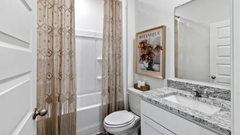 The main level features a spacious, full-sized bathroom equipped with a vanity, single sink, toilet, and a shower tub.
