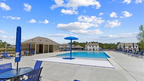 Beautiful community pool surrounded by green grass and blue sky