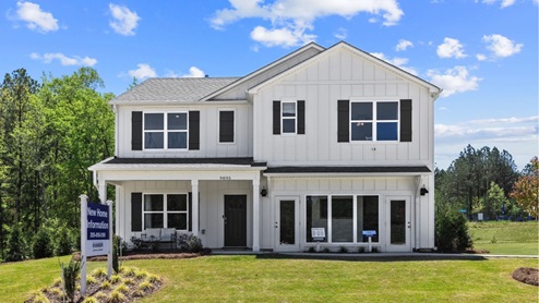 A white two story home surrounded by green grass and blue sky in Chelsea Alabama.