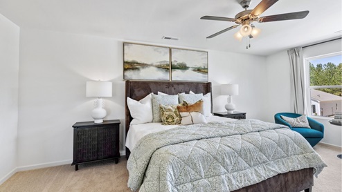 The expansive primary bedroom on the second level features a spacious, king-sized bed. Additionally, there are two oversized night tables, a dresser, and two large guest chairs for added comfort and convenience.