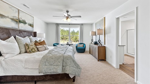 The expansive primary bedroom on the second level features a spacious, king-sized bed. Additionally, there are two oversized night tables, a dresser, and two large guest chairs for added comfort and convenience.