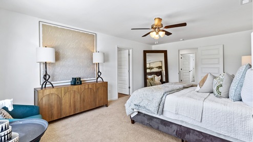 The expansive primary bedroom on the second level features a spacious, king-sized bed. Additionally, there are two oversized night tables, a dresser, and two large guest chairs for added comfort and convenience.