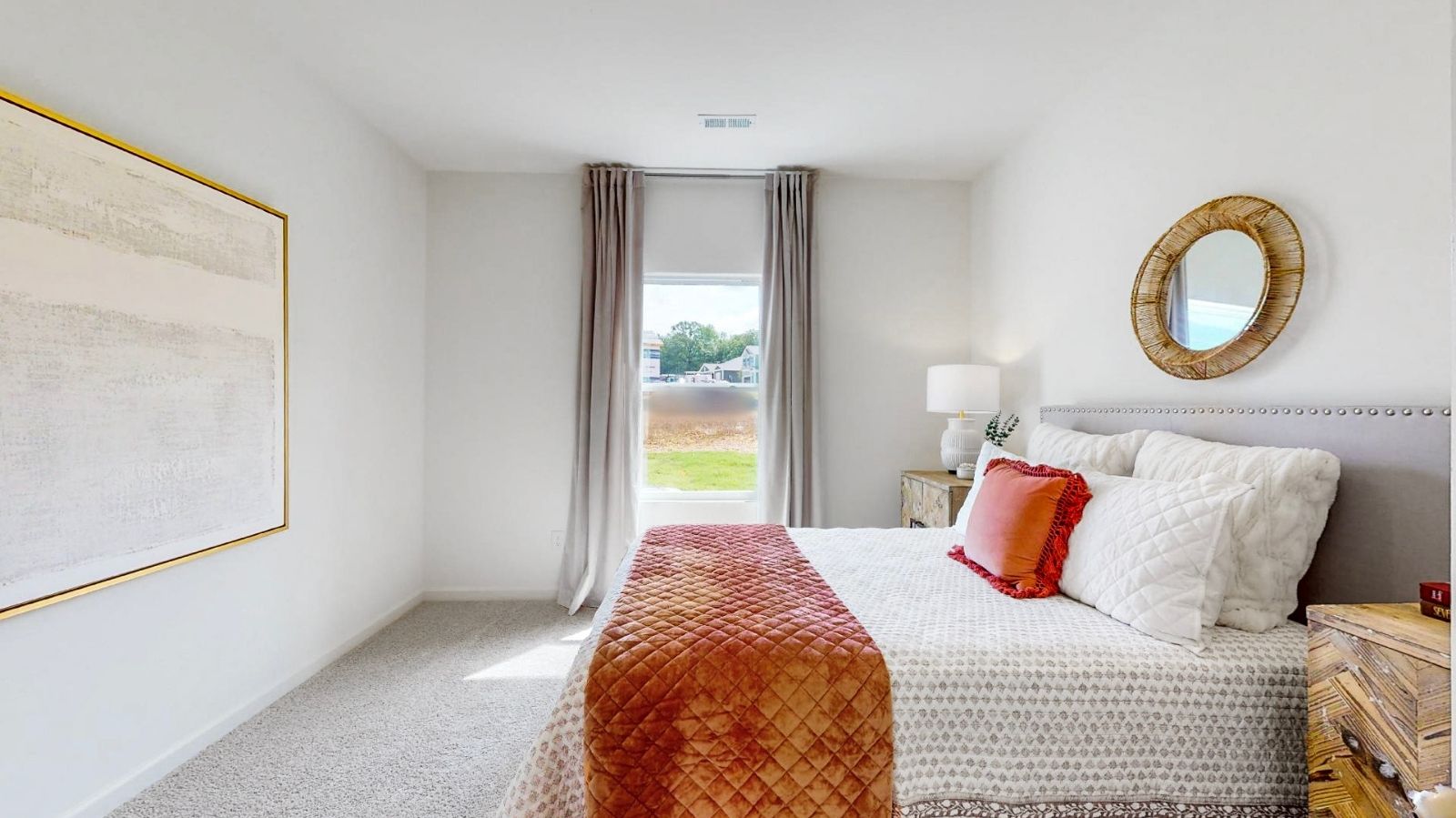 A cozy bedroom featuring a white bed adorned with a vibrant orange bedspread, creating a warm and inviting atmosphere.